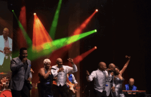 Image Of Top Shelf Classics Band Performing On Stage With Musical Instruments And Vocalists.