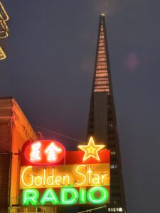 Restored Golden Star Radio Neon Sign Illuminated Beneath The Transamerica Pyramid At Night